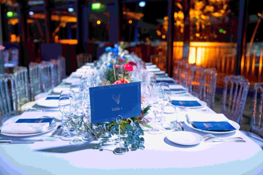 Elegant gedeckter Tisch mit Gläsern, Tellern und Blumenarrangements für eine Veranstaltung.