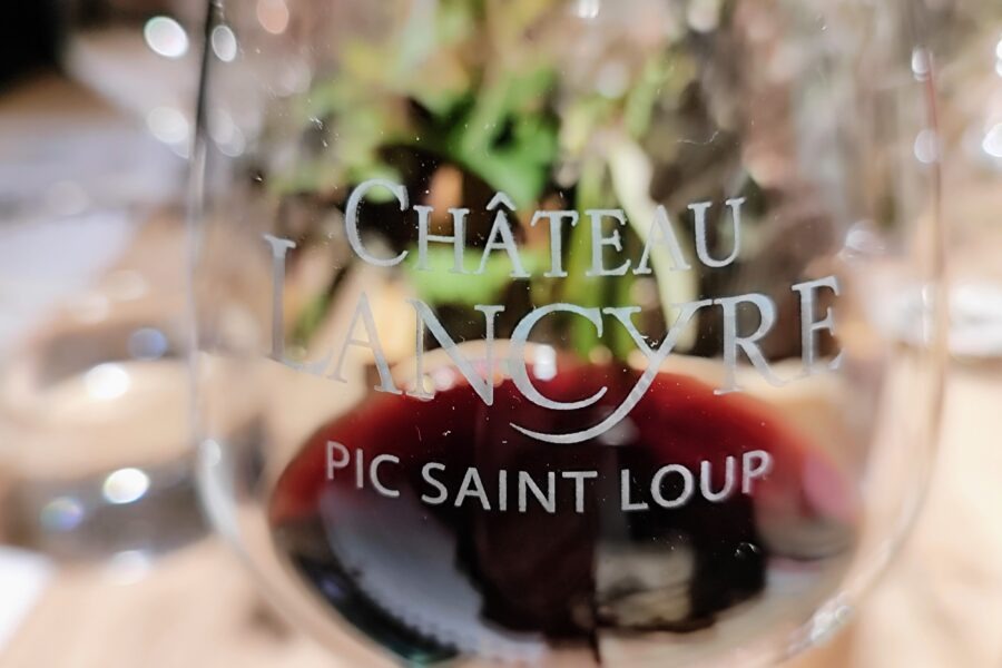 Weinglas mit der Aufschrift 'Chateau Lancyre Pic Saint Loup' und Rotwein im Glas.