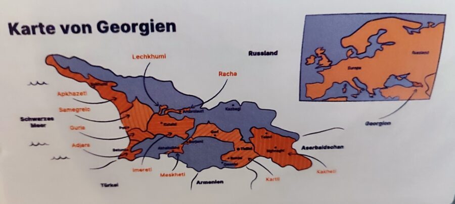Karte von Georgien mit Regionen wie Racha und Kachetien sowie Nachbarländern, blau-orange Farbflächen und klar beschrifteten Gebieten.